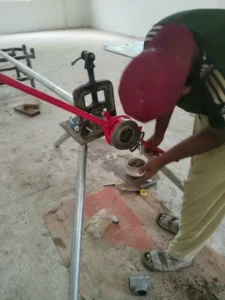 Expert pipe threading and plumbing fitting work on site.